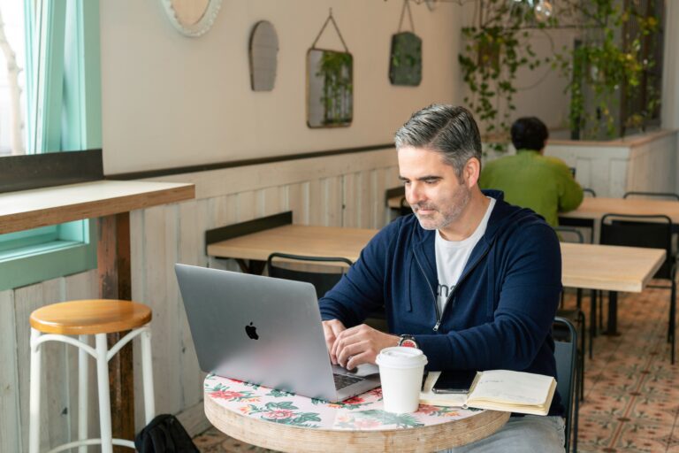 Store owner updating prices from laptop in cafe